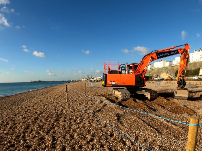Picture of a digger moving pebbles on the beach