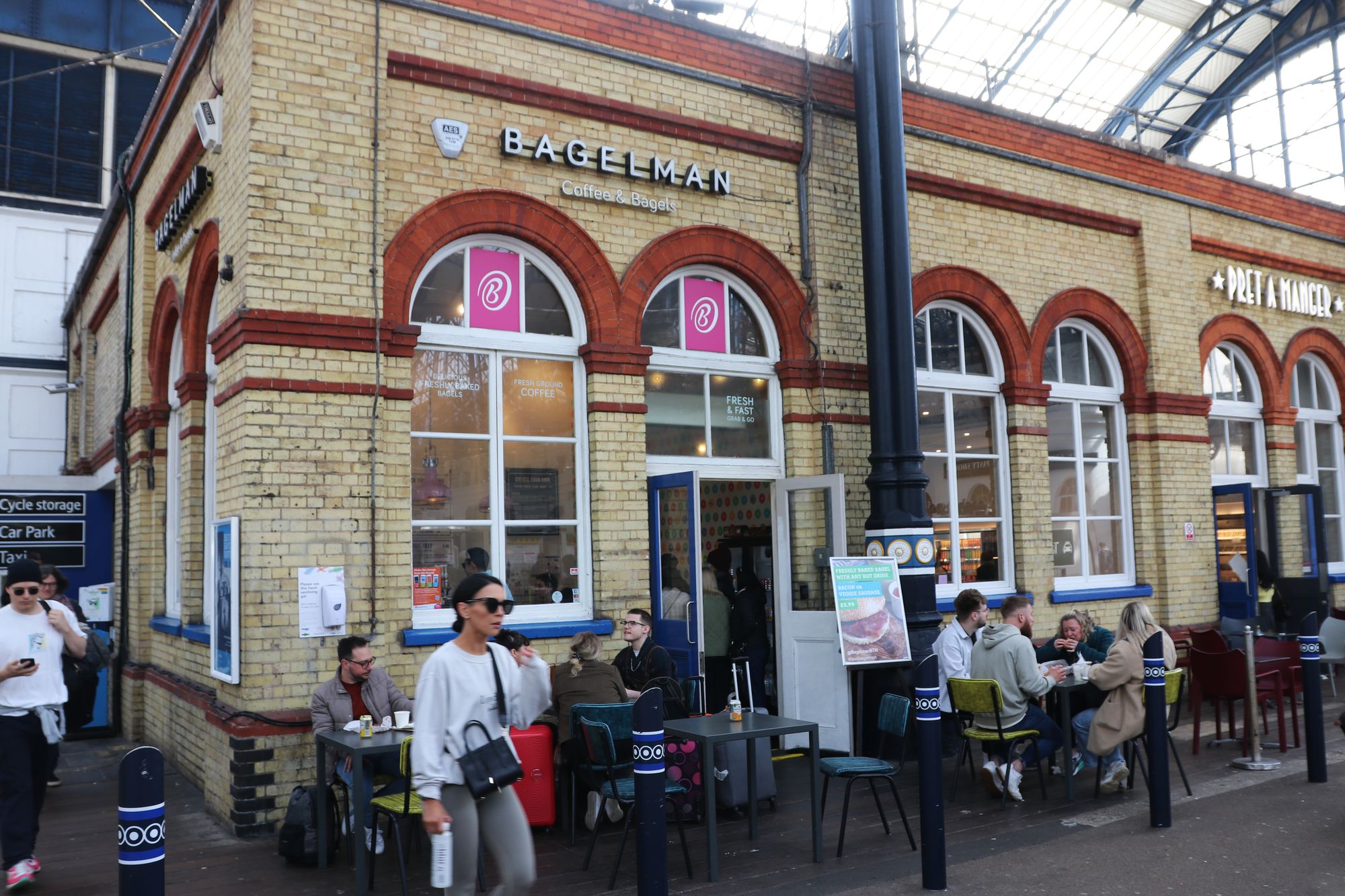 A wide shot of the outside of Bagelman, showing full tables of people eating.
