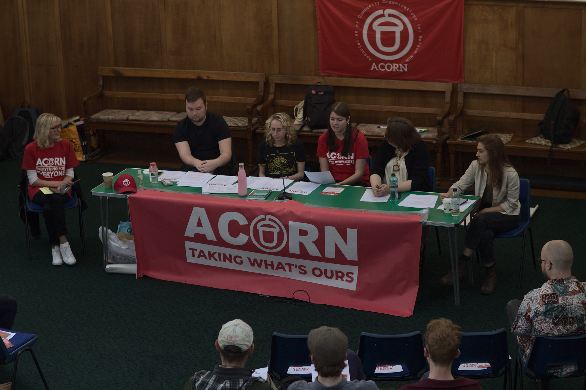A picture of a number of people sitting at a table with an ACORN flag on the front