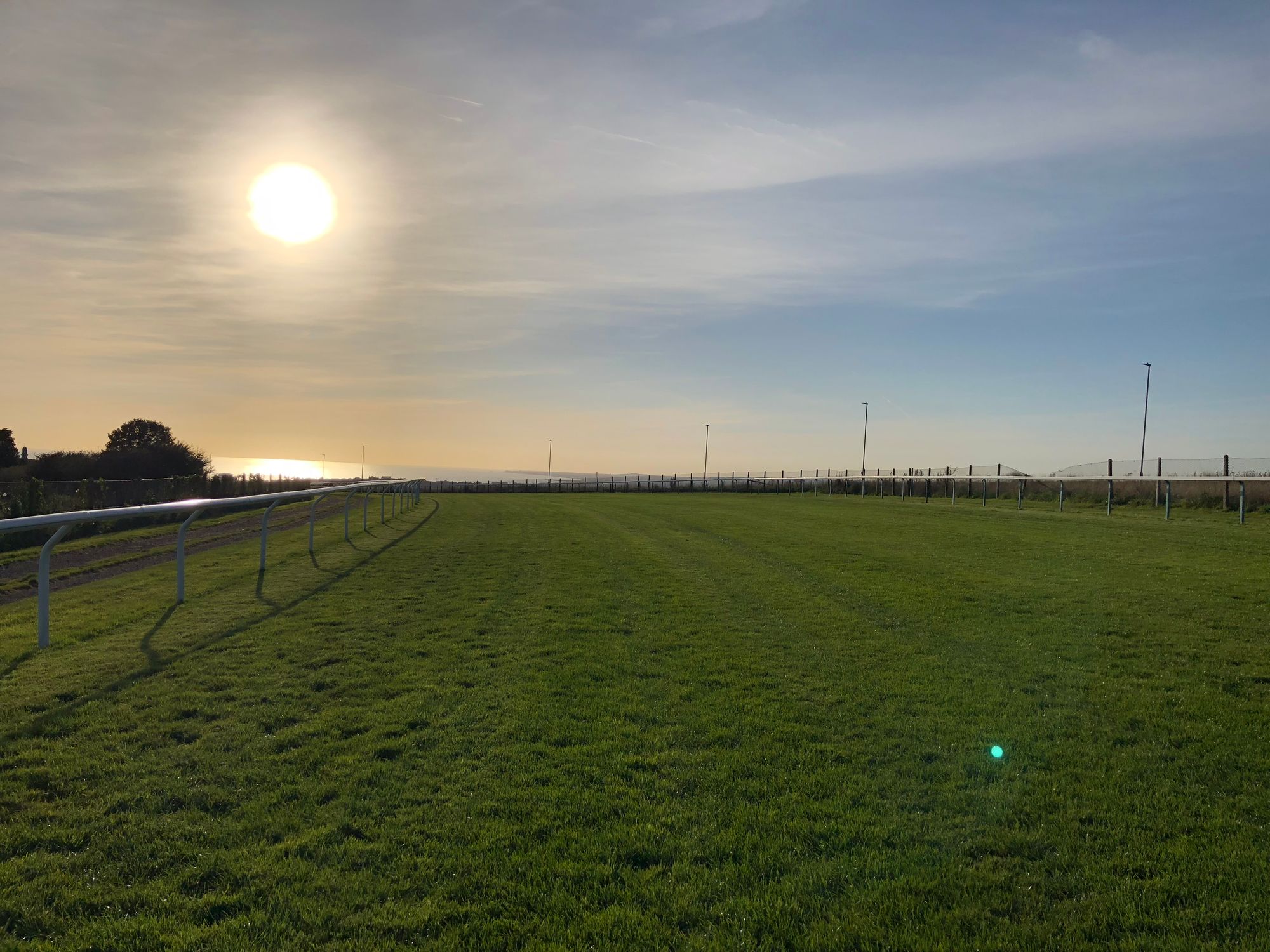Picture of the sun high in the sky over the racecourse, with views down to the sea