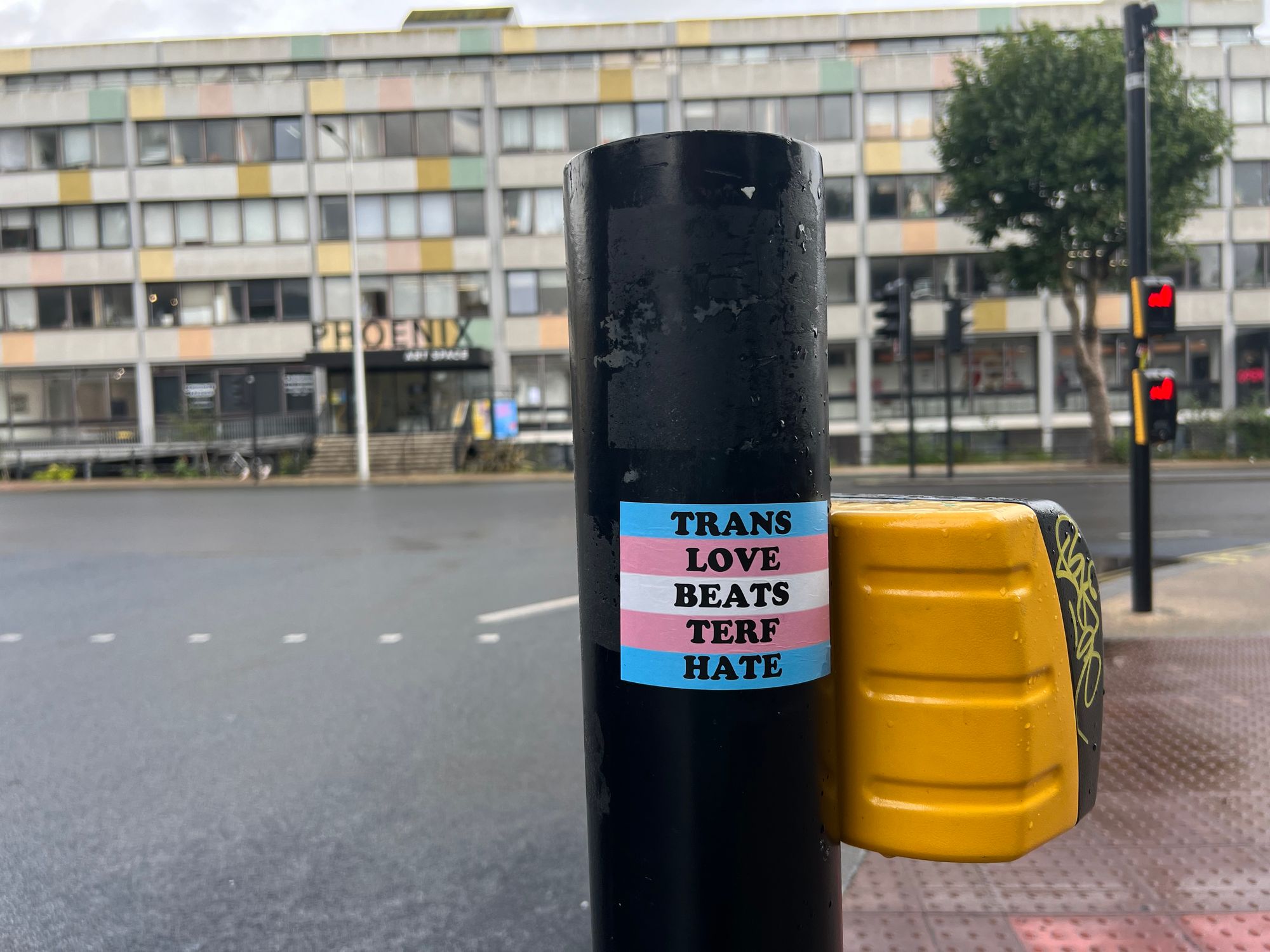 A "Trans Love Beats Terf Hate" sticker on a traffic light pole in front of the Phoenix Art Space