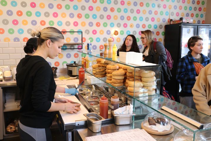 The inside of Bagelman at Brighton Station, with customers waiting for bagels and staff making them.