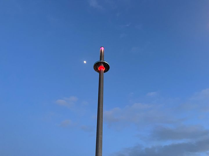 A picture of the i360 from below with the moon in the background